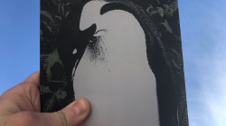 a hand holding a book cover of a penguin